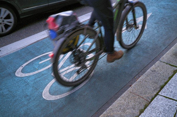Bicycle, cyclist, rides on cycle path, pictogram, logo, labelling, next to road, car, motion effect, speed, Stuttgart, Baden-Württemberg, Germany
