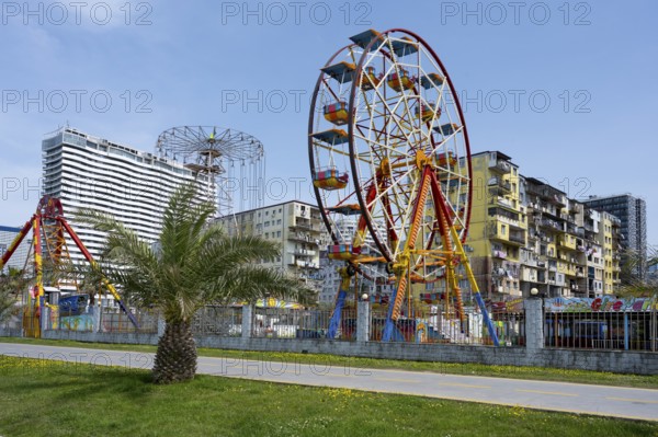 A colourful amusement park with a Ferris wheel against an urban backdrop under a clear sky, amusement park, Batumi, Black Sea, Adjara region, Adjara, autonomous republic, Georgia