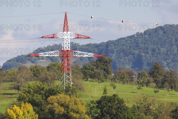 High-voltage pylon with signalling paint in front of the landscape of the Swabian Alb. Kirchheim unter Teck, Baden-Württemberg, Germany