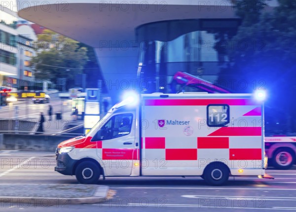 Ambulance of the BOS organisation Malteser with blue lights in an urban environment. Pulling along. Stuttgart, Baden-Württemberg, Germany