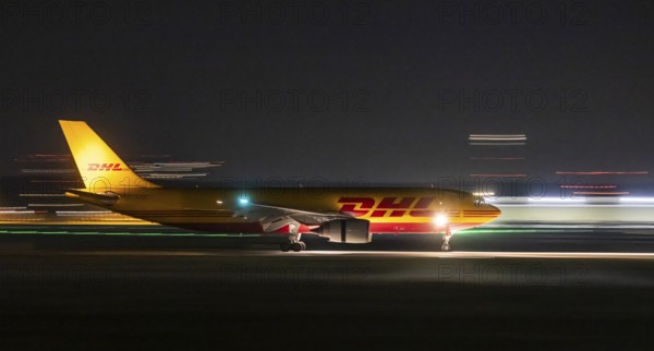 Stuttgart Airport in the early morning. DHL cargo plane landing. Light traces with motion blur. Stuttgart, Baden-Württemberg, Germany