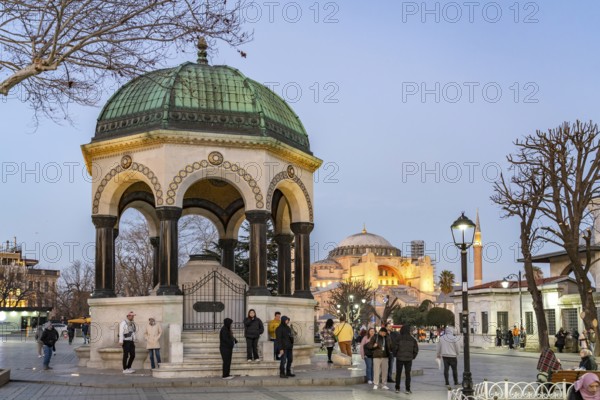 Tourists at the German Fountain or Kaiser Wilhelm Fountain and the Hagia Sophia at dusk, Istanbul, Turkey