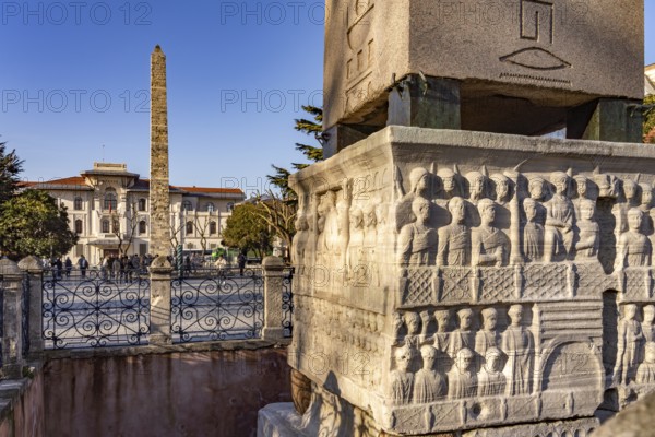 Marble base of the ancient Egyptian Obelisk of Theodosius or Obelisk of Istanbul with reliefs and the Column of Constantine or Masonry Obelisk at the Hippodrome in Istanbul, Turkey