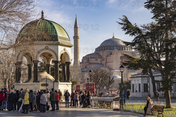 Tourists at the German Fountain or Kaiser Wilhelm Fountain and the Hagia Sophia or Church of St Sophia, former Byzantine church and museum in Istanbul, Turkey