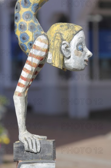 Sculpture Die Literaturnerin by Hans Scheib 2007, Modern Art, Girl figure doing a handstand on a pile of books with striped clothes, acrobatic, standing on her head, wood sculpture, detail, Adenauerplatz, Wiesloch, Baden-Württemberg, Germany