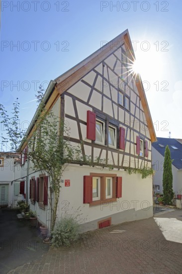 Half-timbered house with red shutters against the light, Höllgasse, Wiesloch, Baden-Württemberg, Germany