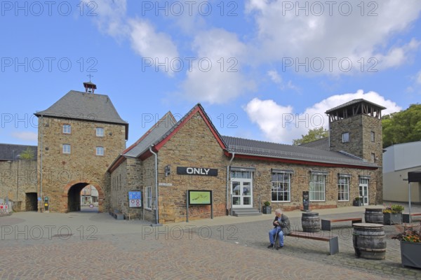 Historic Orchheim Tor, town gate, town tower, town fortification, town wall, person sitting on a bench, Bad Münstereifel, Ahrgebirge, Eifel, North Rhine-Westphalia, Germany