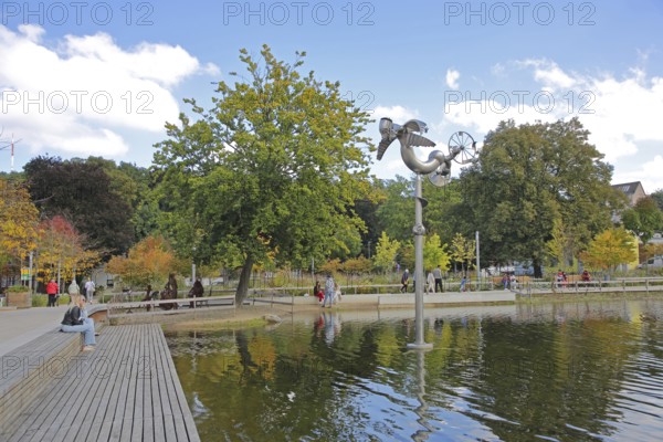Bastinsweiher with sculpture, seating, bench, people, pedestrians, park, pond, autumn colours, Rhineland, Stolberg, North Rhine-Westphalia, Germany