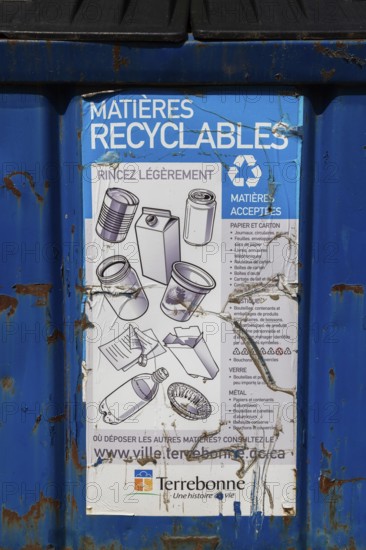 Close-up of accepted recyclable materials list on blue metal with black plastic lid industrial size recycling bin, Ile des Moulins, Old Terrebonne, Quebec, Canada