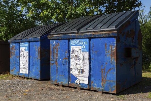Blue metal with black plastic lid industrial size recycling bins for depositing glass, metal and plastic containers in, Ile des Moulins, Old Terrebonne, Quebec, Canada