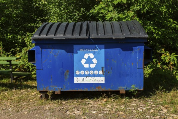 Blue metal with black plastic lids industrial size recycling bin for depositing glass, metal and plastic containers in, Ile des Moulins, Old Terrebonne, Quebec, Canada