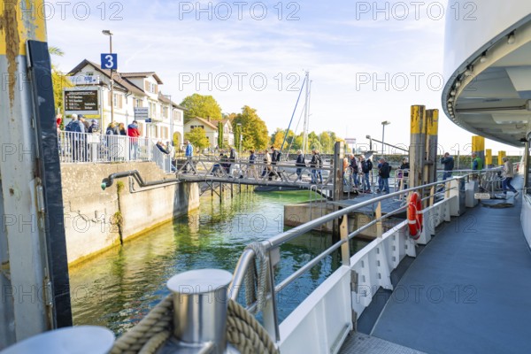 View from the ferry deck to the shore with waiting passengers and autumn foliage, Meersburg, Lake Constance, Germany