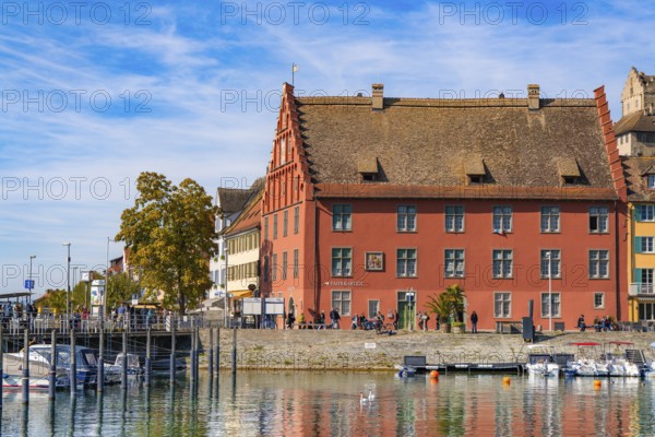 Historic building with red façade on the waterfront next to a harbour, Meersburg, Lake Constance, Germany