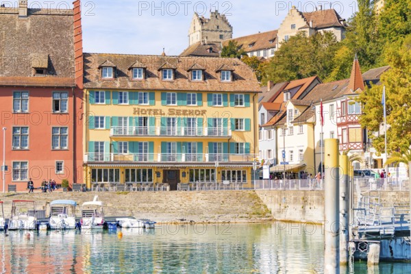 Hotel building with colourful facades on the shore and docked boats in sunny weather, Meersburg, Lake Constance, Germany