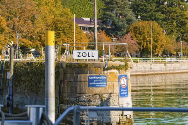 Customs office in the harbour area surrounded by water and autumnal vegetation, Meersburg, Lake Constance, Germany