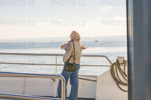 Woman on boat looking at the sea, wearing scarf, relaxed atmosphere, Meersburg, Lake Constance, Germany