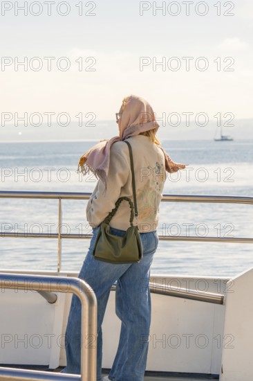 Woman looking at the sea from the boat, wearing scarf and jeans, relaxed mood, Meersburg, Lake Constance, Germany