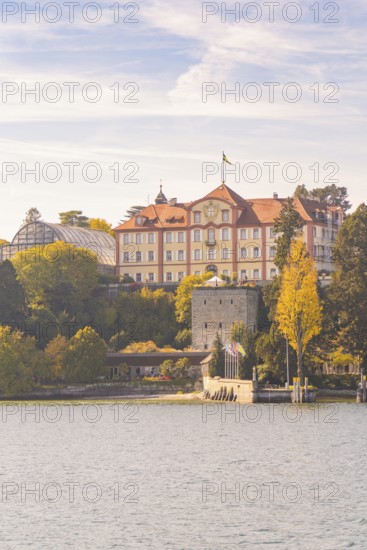 Historic castle on the lake with autumn trees and cloudy sky, Mainau Island, Lake Constance, Germany