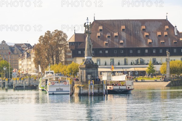 Harbour with a statue, several buildings and adjacent ships on a calm water, Constance, Lake Constance, Germany