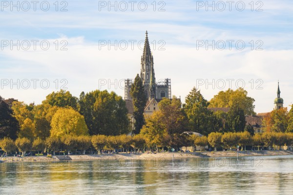 Impressive church tower with surrounding autumnal trees on the riverside, Constance, Lake Constance, Germany