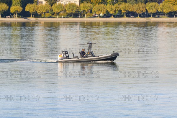 Police motorboat with two people travelling over calm water near the shore, Constance, Lake Constance, Germany