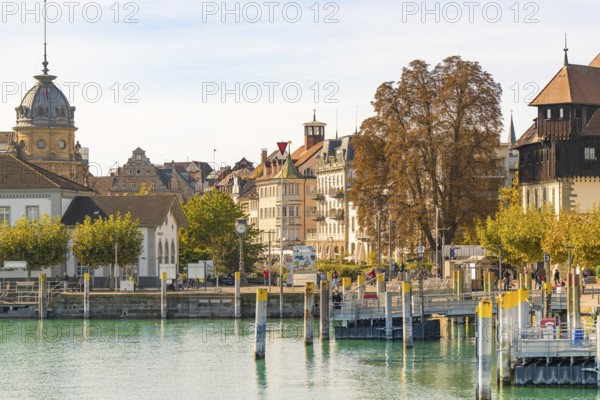 Urban harbour scene with historic and modern buildings, surrounded by trees and calm water, Constance, Lake Constance, Germany