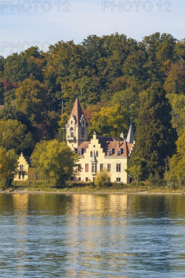 A historic manor house nestled in autumnal trees on the shore of a tranquil lake, Constance, Lake Constance, Germany