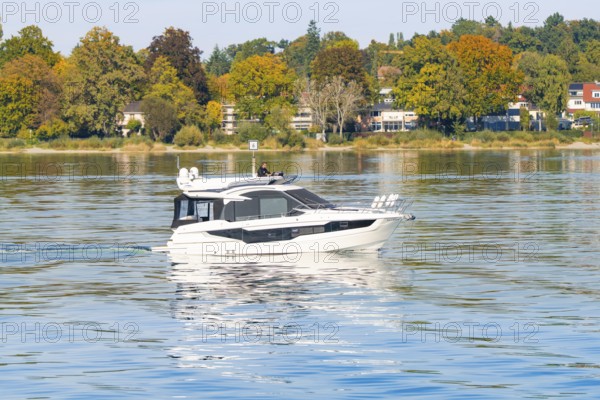 Luxurious white yacht sails on a calm lake surrounded by autumnal trees, Constance, Lake Constance, Germany