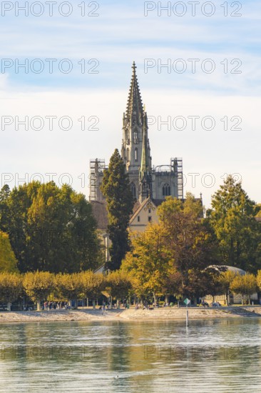 Majestic church tower surrounded by autumnal trees under a clear sky, Constance, Lake Constance, Germany