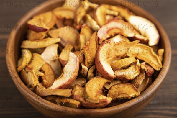Dried Apples in wooden bowl on brown wooden background. Side view, close up, healthy food, minimalism. sweet, selective focus