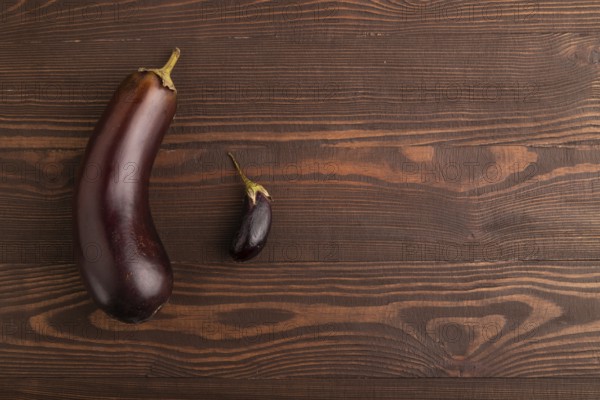 Two Eggplants big and small on brown wooden background, top view, flat lay, copy space, minimalism