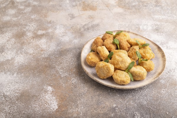 Fried crispy Chicken Nuggets with ketchup, microgreen on brown concrete background. side view, copy space