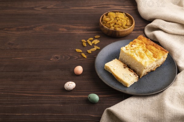 ?ottage cheese ?asserole, Curd cake, with dried apricots and raisins on brown wooden background and linen textile, side view, copy space, minimalism