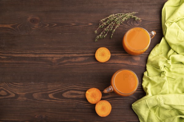 Two glasses with carrot juice, on wooden background and green textile. Diet, healthy eating concept. top view, flat lay, copy space, minimalism
