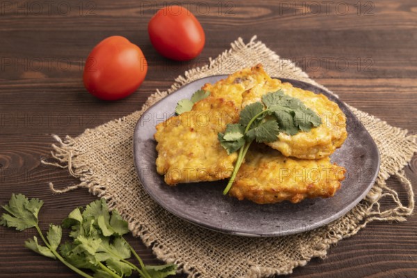 Fried crispy Chicken pancakes on brown wooden background and linen textile. side view, close up