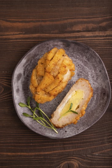 Chicken Schnitzel on gray plate with microgreen on brown wooden background. top view, flat lay, copy space
