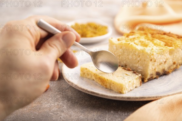?ottage cheese ?asserole, Curd cake, with dried apricots and raisins with hand on brown concrete background and orange textile, side view, selective focus, minimalism