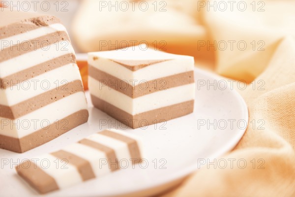 Cocoa and milk jelly with dried apricots on brown concrete background and orange textile, side view, close up, selective focus, minimalism