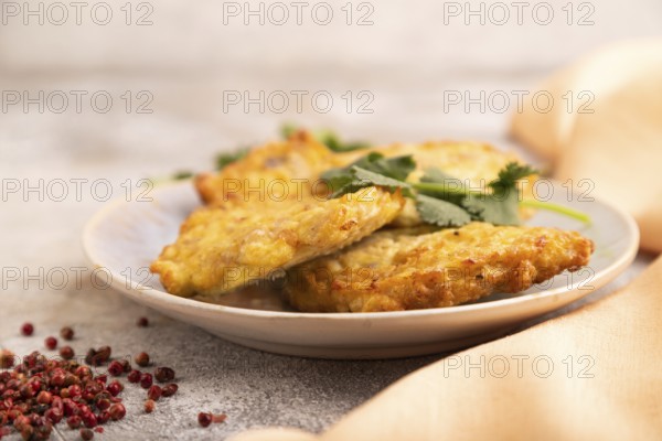 Fried crispy Chicken pancakes on brown concrete background and orange linen textile. side view, close up, selective focus
