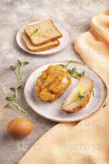 Chicken Schnitzel on blue plate with microgreen on brown concrete background and orange linen textile. side view, close up