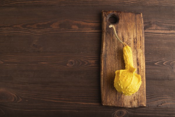 Decorative orange Pumpkin on cutting board on brown wooden background, top view, flat lay, copy space, minimalism