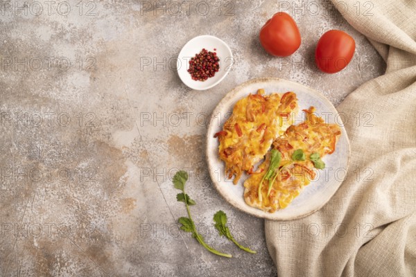 Baked chicken meat with cheese and tomatoes on brown concrete background and linen textile. top view, flat lay, copy space