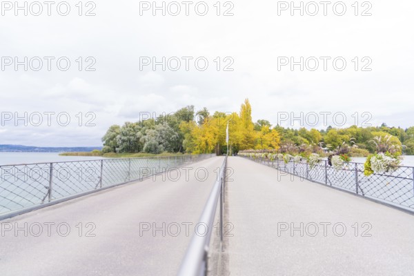 Long bridge over the water, flanked by autumn-coloured trees in shades of yellow and green, Mainau Island, Lake Constance, Germany