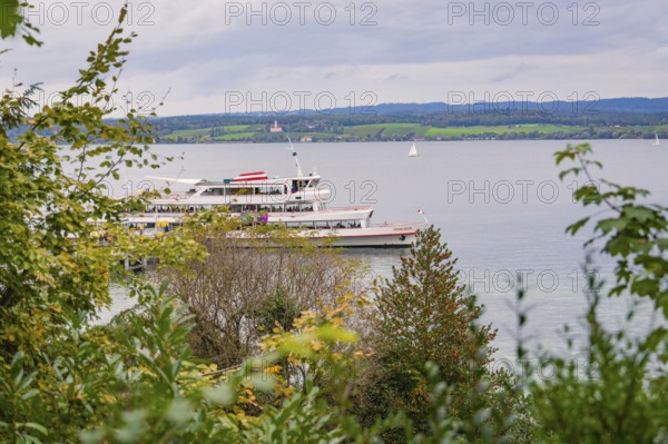 A large lake with a boat, surrounded by green landscape and cloudy sky, Mainau Island, Lake Constance, Germany