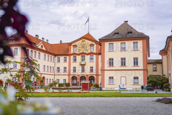 Large castle with architectural details, surrounded by a well-tended garden and visitors, Mainau Island, Lake Constance, Germany