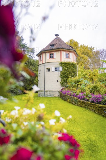 Tower-like building surrounded by flowering garden and green meadow, Mainau flower island, Lake Constance, Germany
