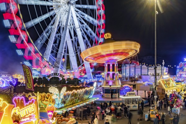 Folk festival in Stuttgart. The 178th Cannstatter Volksfest on the Wasen is one of the most important traditional festivals in Germany. Ferris wheel, chain carousel and other amusement park attractions, light effects at night. Stuttgart, Baden-Württemberg, Germany