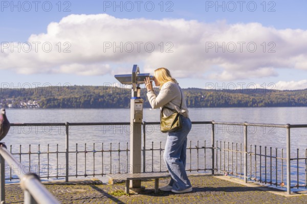 Woman using binoculars to look out over the lake from a platform, Überlingen, Lake Constance, Germany