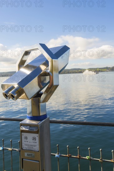 Binoculars on the shore with a ship in the background on the calm lake, Überlingen, Lake Constance, Germany