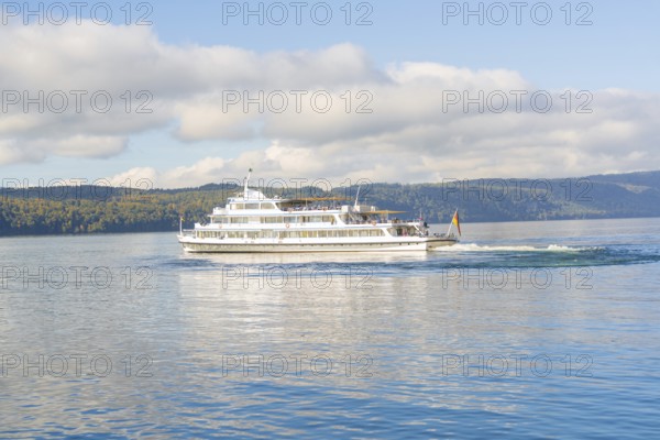 White ship sailing across a clear lake against a picturesque mountain backdrop, Überlingen, Lake Constance, Germany